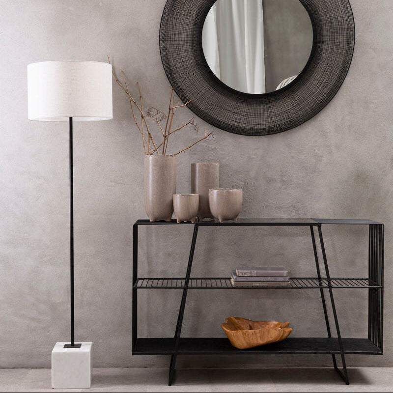 Modern interior with a round mirror, console table, and floor lamp against a gray wall.