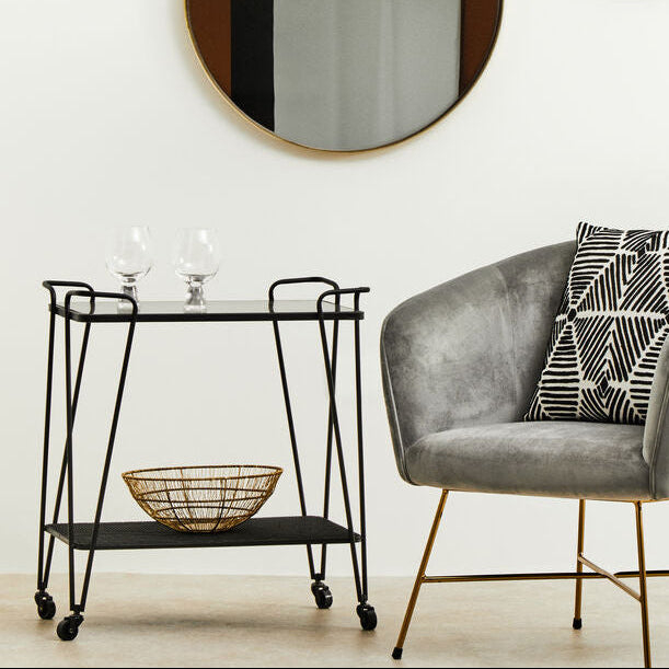 Modern interior with a gray armchair, side table, and wall mirrors.