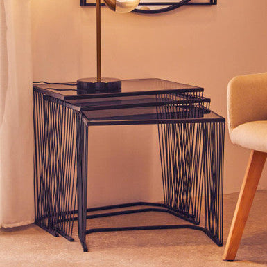 Set of black wire side tables with a lamp in a room setting.