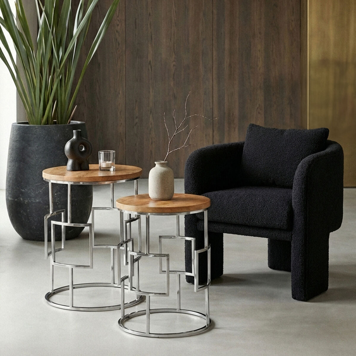 Modern living room with black armchair, wooden side tables, and decorative items.