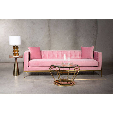Pink sofa with gold coffee table and side table against a gray wall.
