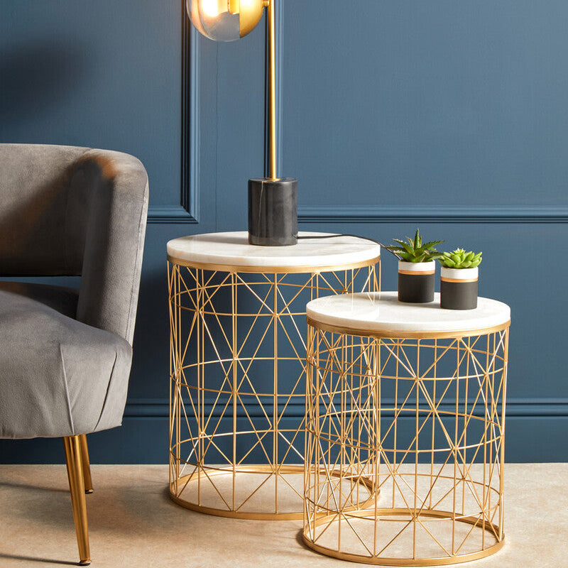 Gold wire side table with marble top against a blue wall