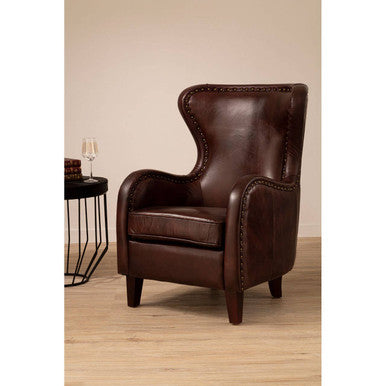 Brown leather armchair in a room with a side table and lamp.