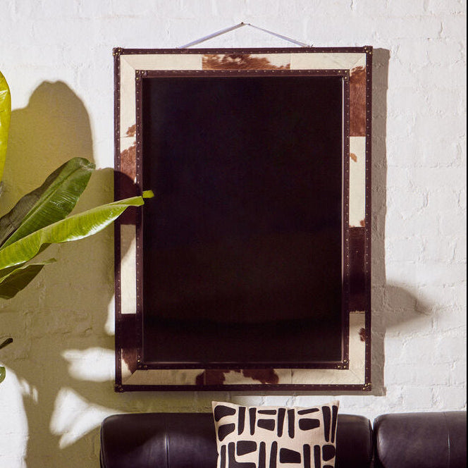 Living room with a brown leather sofa, decorative pillow, potted plant, and mirror.