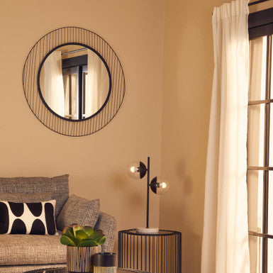 Modern living room with a round wire coffee table, mirror, and sofa.