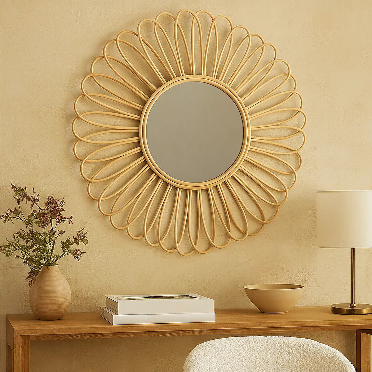 Decorative wall mirror with floral design on a beige wall above a wooden console table.