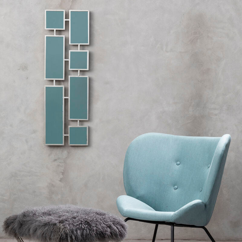 Light blue chair with a gray ottoman and decorative wall art in a room with gray walls.
