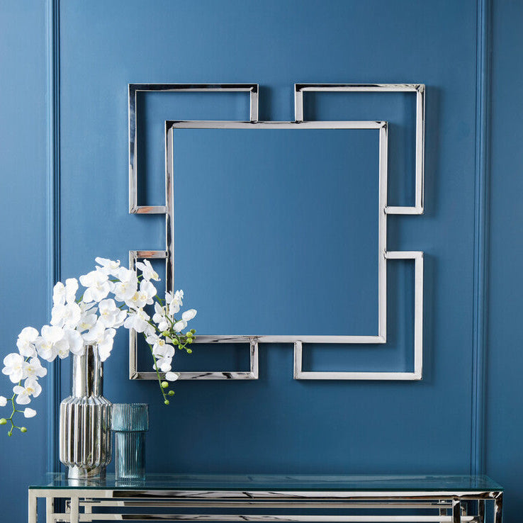 Decorative console table with mirror and flowers against a blue wall