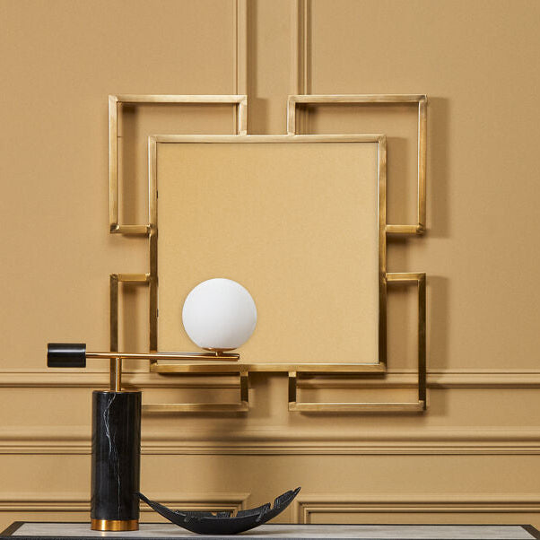 Decorative console table with a lamp and mirror against a beige wall.
