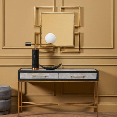 Decorative console table with a mirror and decorative items against a beige wall.