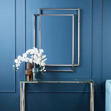 Modern console table with decorative flowers against a blue wall