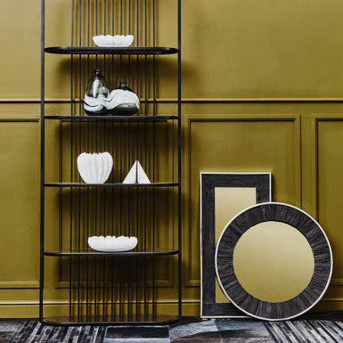 Black metal shelving unit with decorative items against a green wall.