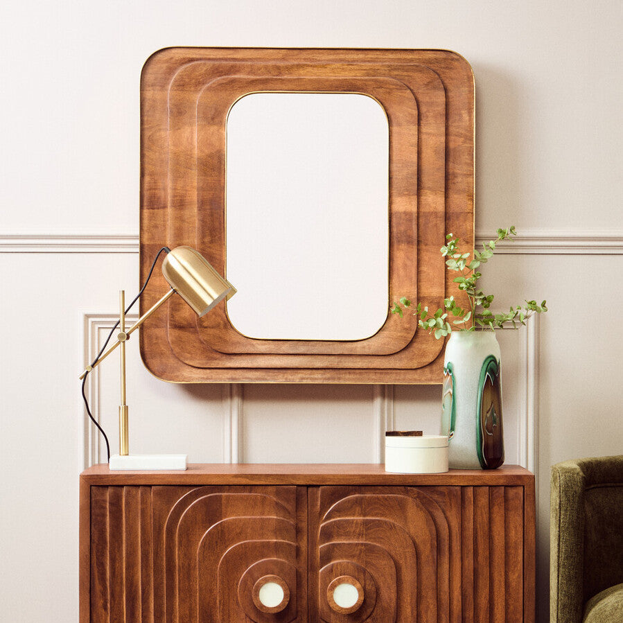 Wooden console table with decorative mirror and lamp in a room setting