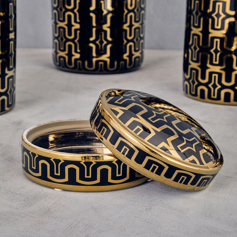 Decorative container with gold and black geometric pattern on a gray surface