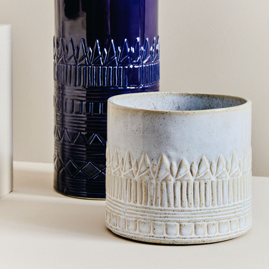 Two ceramic vases, one blue and one beige, on a light background