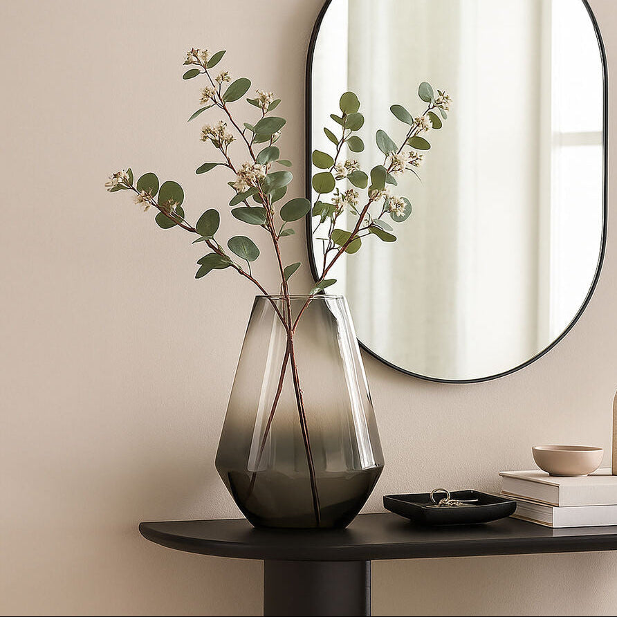Round mirror on a beige wall above a dark wooden console table with decorative items.