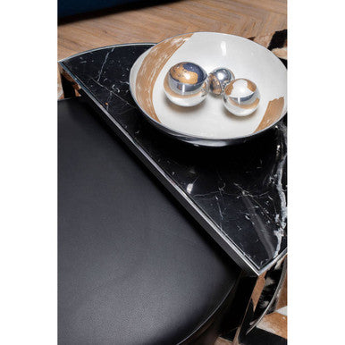 Black marble coffee table with a decorative plate featuring candles on a wooden floor.