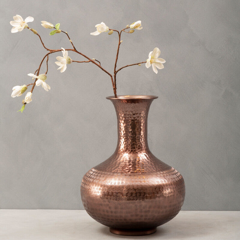 Copper vase with floral branch on a gray background