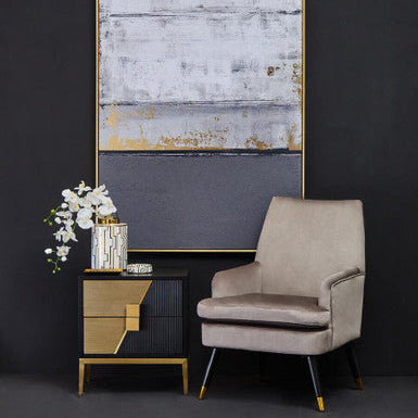Modern interior with a beige armchair, side table, and abstract painting against a dark wall.