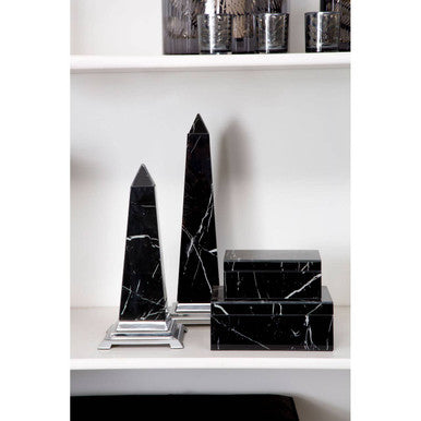 Black marble obelisks on a white surface with a neutral background