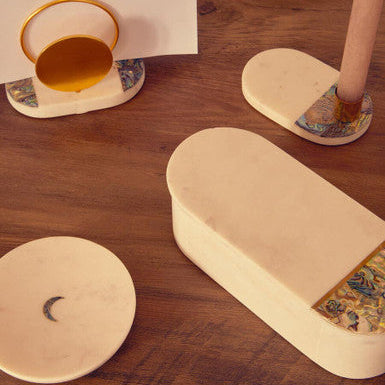 Decorative items including a cylindrical box, coasters, and a small cup on a wooden surface.