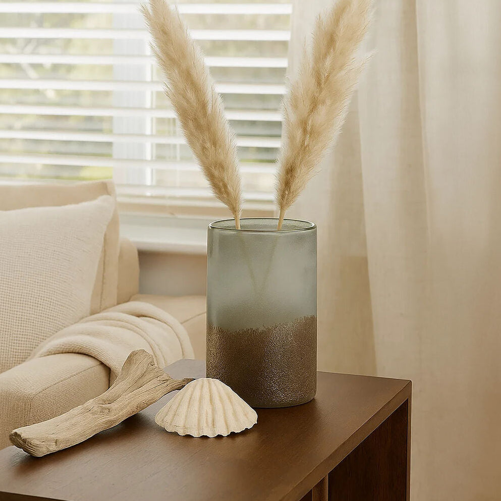 Decorative vase with pampas grass on a table next to a sofa and shell