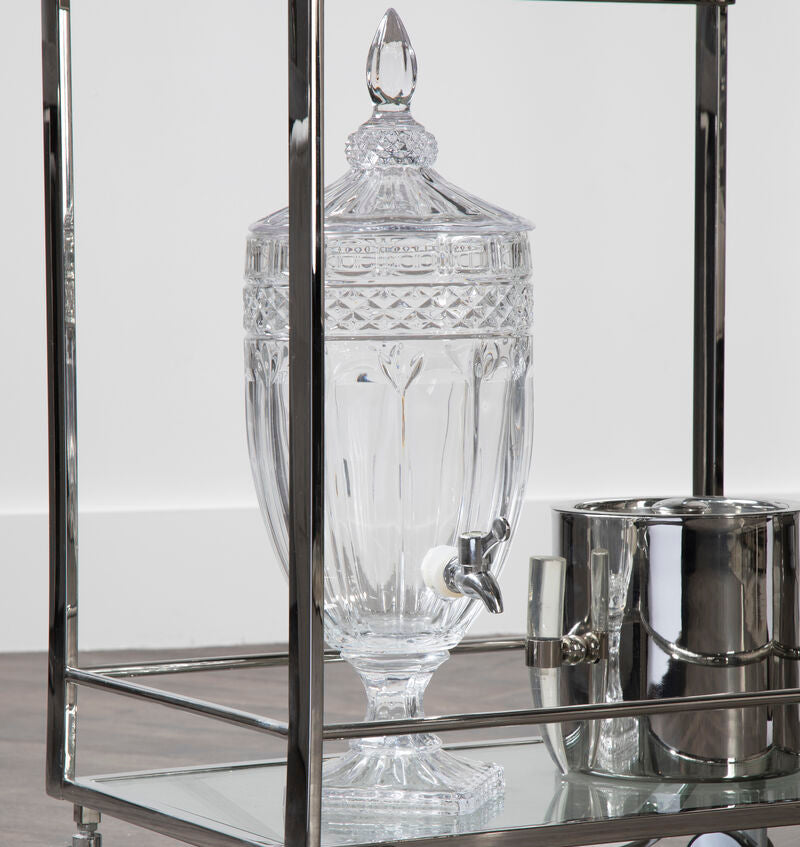 Decorative glass container on a metal bar cart with a white background