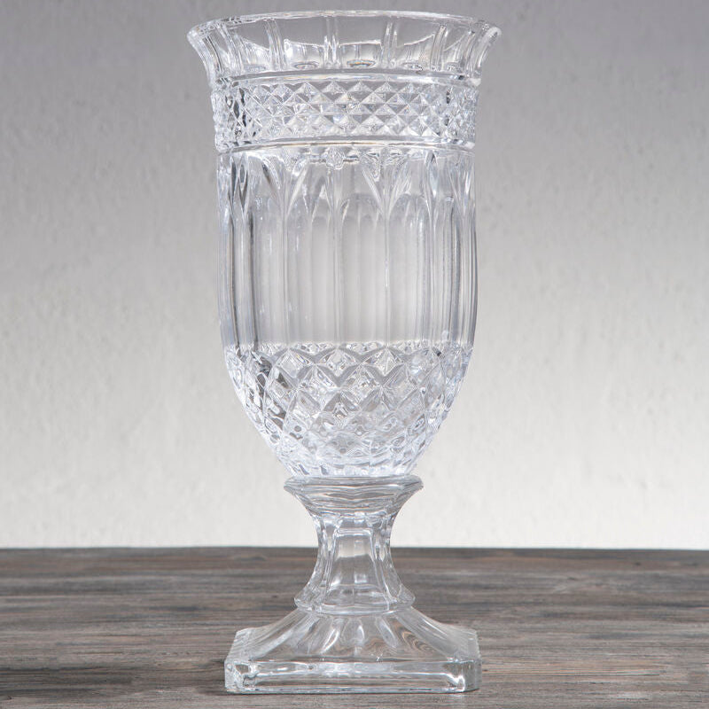 Clear glass vase with diamond cut pattern on a wooden surface and gray background