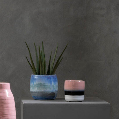 Vases with gradient colors on gray pedestals against a dark gray background