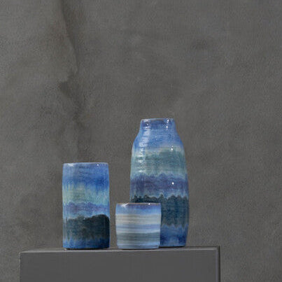 Collection of ceramic vases with blue and pink glaze on a gray background
