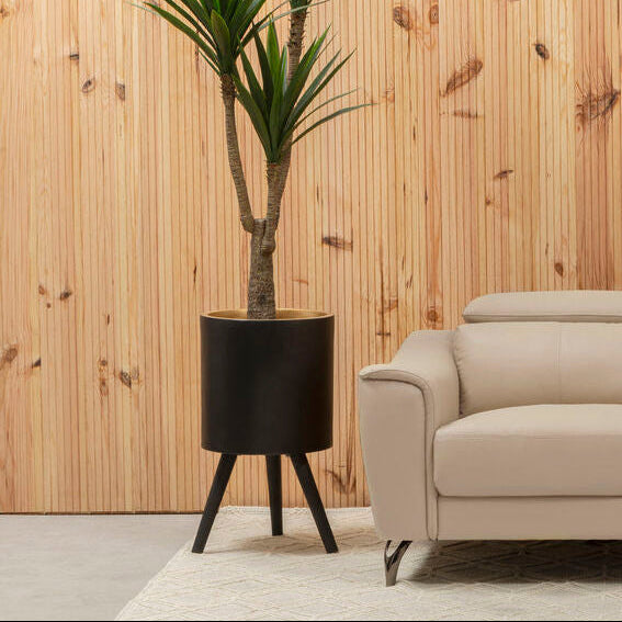 Beige sofa in a modern living room with a wooden wall and plant.