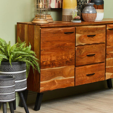 Wooden dresser with decorative items and plants against a green wall