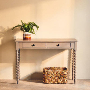 Wooden console table with a plant and basket against a plain wall