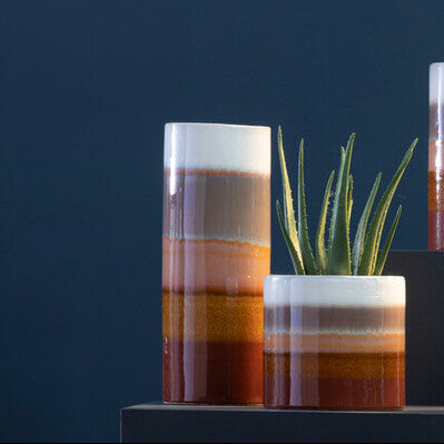 Collection of ceramic vases with striped patterns on a dark blue background