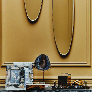 Decorative console table with a gold wall and abstract art in a stylish interior setting.