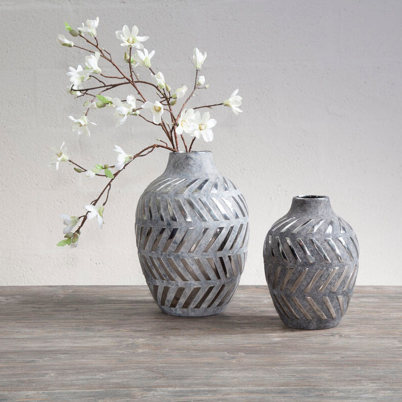 Two gray textured vases on a wooden surface with a white background