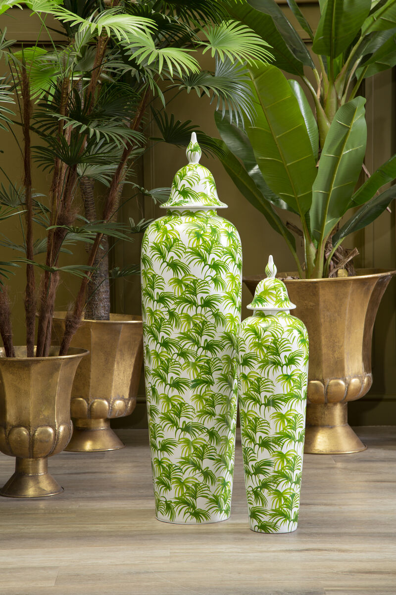 Two green and white patterned vases on a wooden surface with plants in the background.