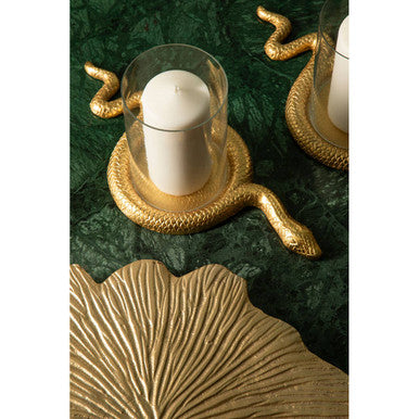 Decorative candle holder with gold snake design on a green surface