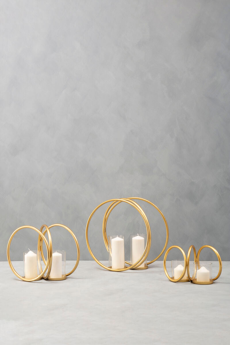 Set of gold circular candle holders with candles on a gray background