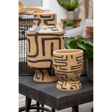 Two terracotta pots with black geometric patterns on a table.