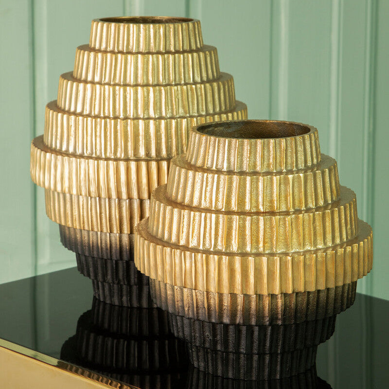 Two decorative vases with a textured design on a reflective surface against a green panel background.