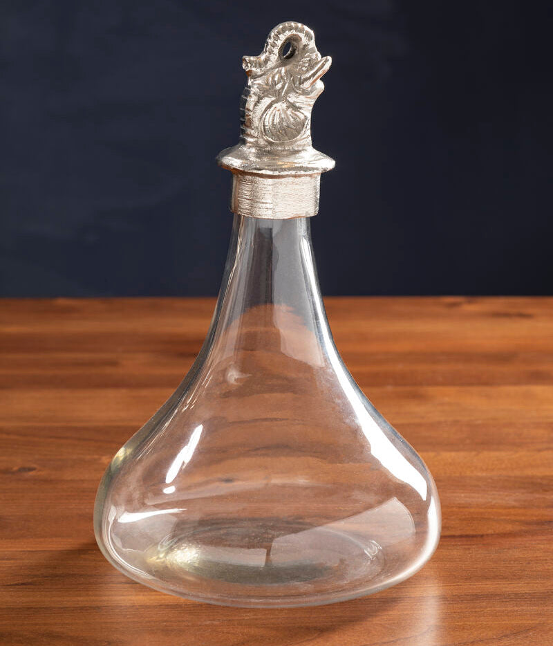 Clear glass decanter with silver stopper on a wooden surface