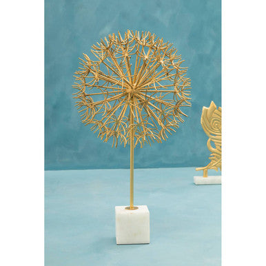 Decorative gold plant sculpture on a white base against a teal background