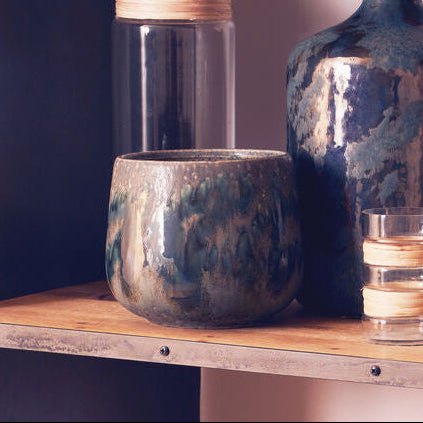 Wooden shelf with decorative vases and glasses against a plain wall