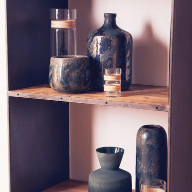 Wooden shelf with decorative vases and glasses against a dark wall.