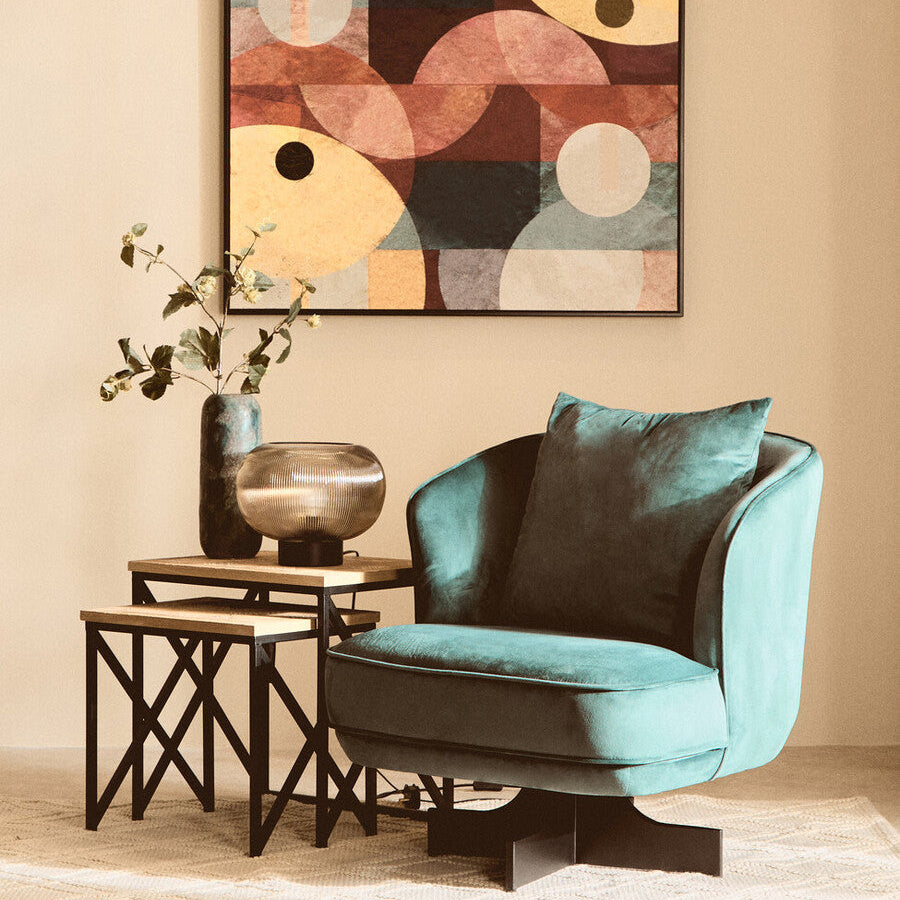 Modern living room with a teal armchair, abstract art, and side table.