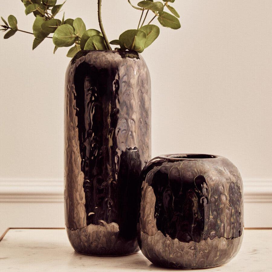 Two rustic ceramic vases with textured surfaces on a light wooden surface.
