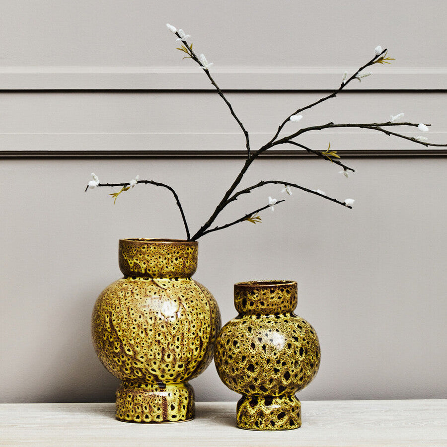 Two decorative vases with a textured design on a light surface against a neutral background.