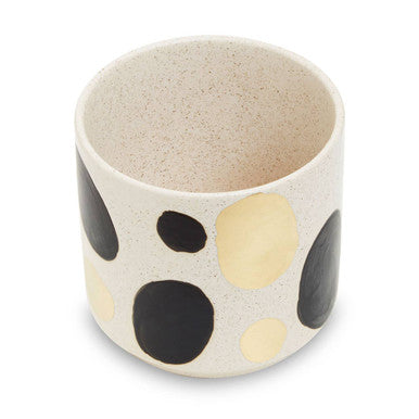 Ceramic cup with black and beige polka dot pattern on a white background