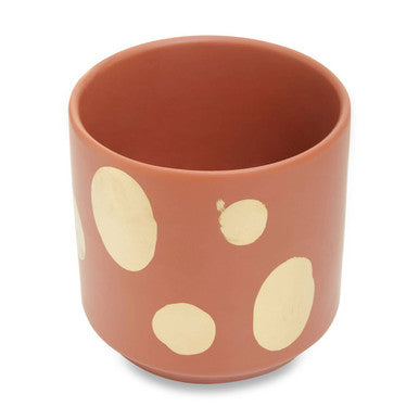 Ceramic cup with beige polka dots on a white background